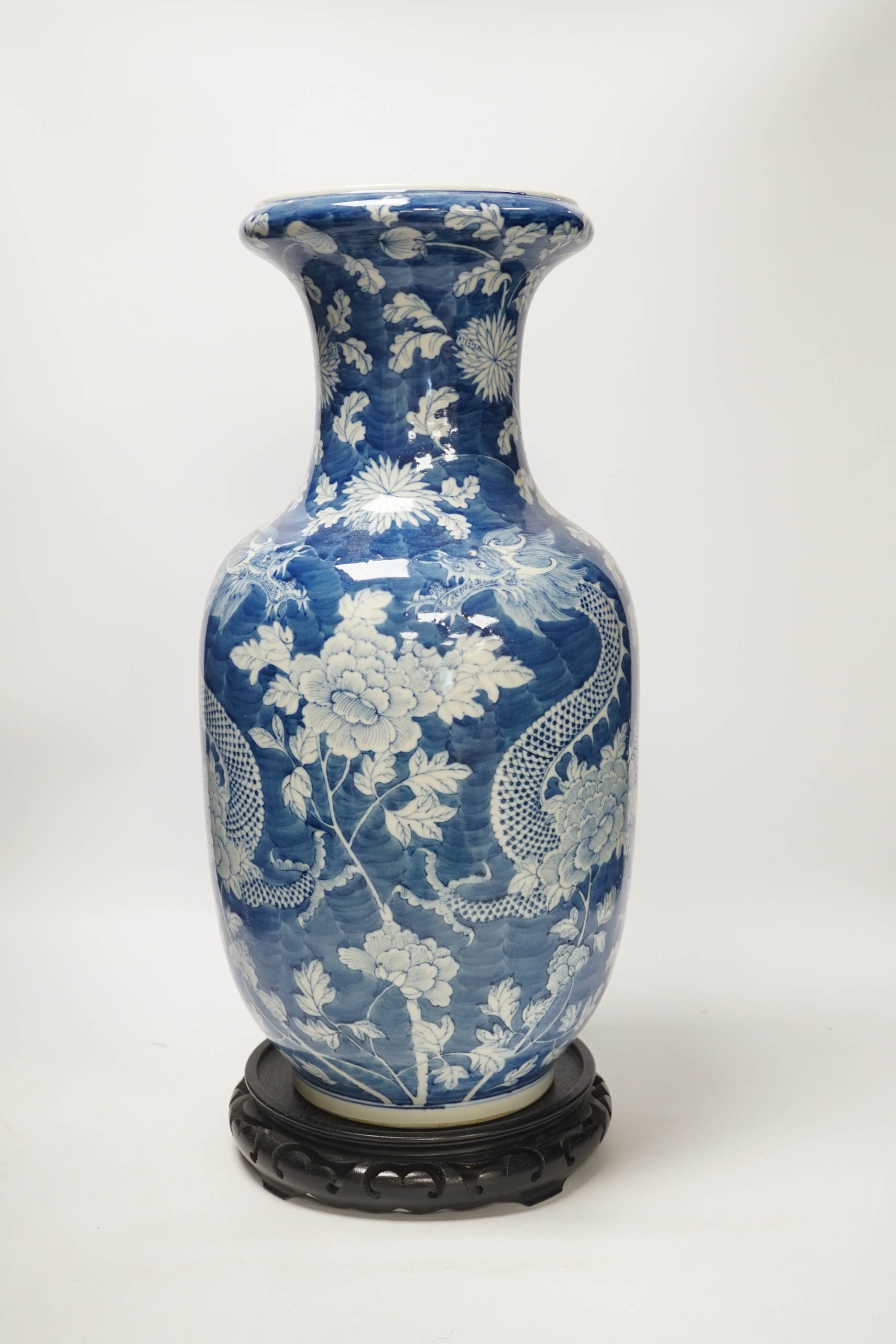 A Chinese blue and white baluster vase decorated with dragons and flowers together with an unassociated carved hardwood stand, 44cm high